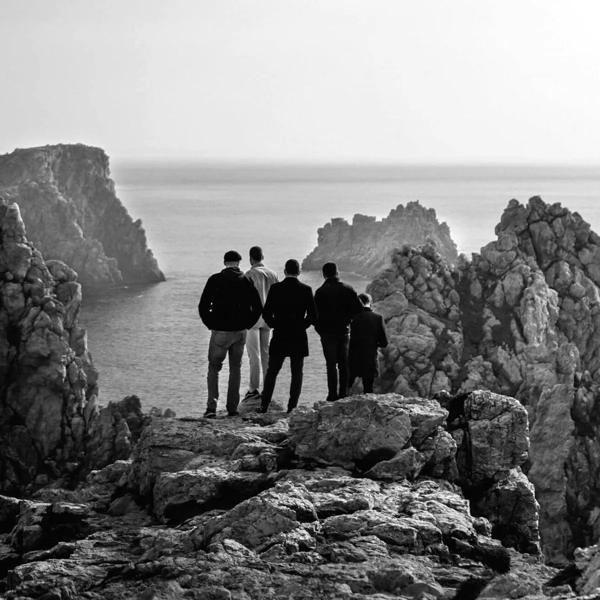Groupe d'hommes sur des rochers en bord de mer